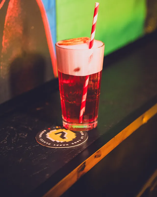 Drink rosso con cannuccia a righe appoggiato sul sottobicchiere con il 7 del 7COINS