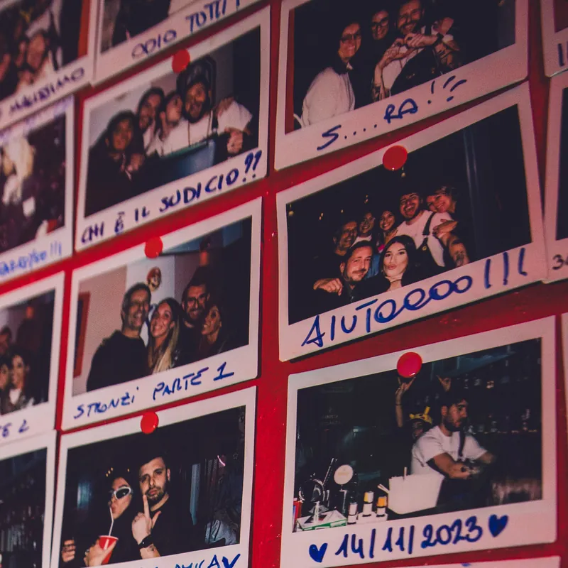 Dettaglio della parete Polaroid: gruppi di amici e dediche come «Chi è il sudicio??» e «Aiutoooo!!!»